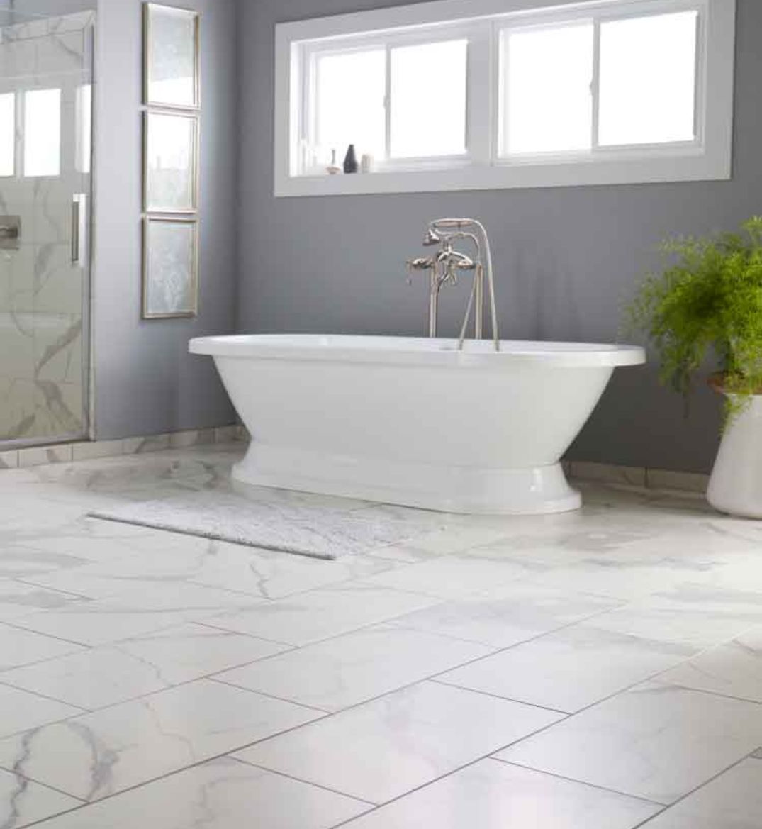 white bathtub near bathroom windows with tile flooring